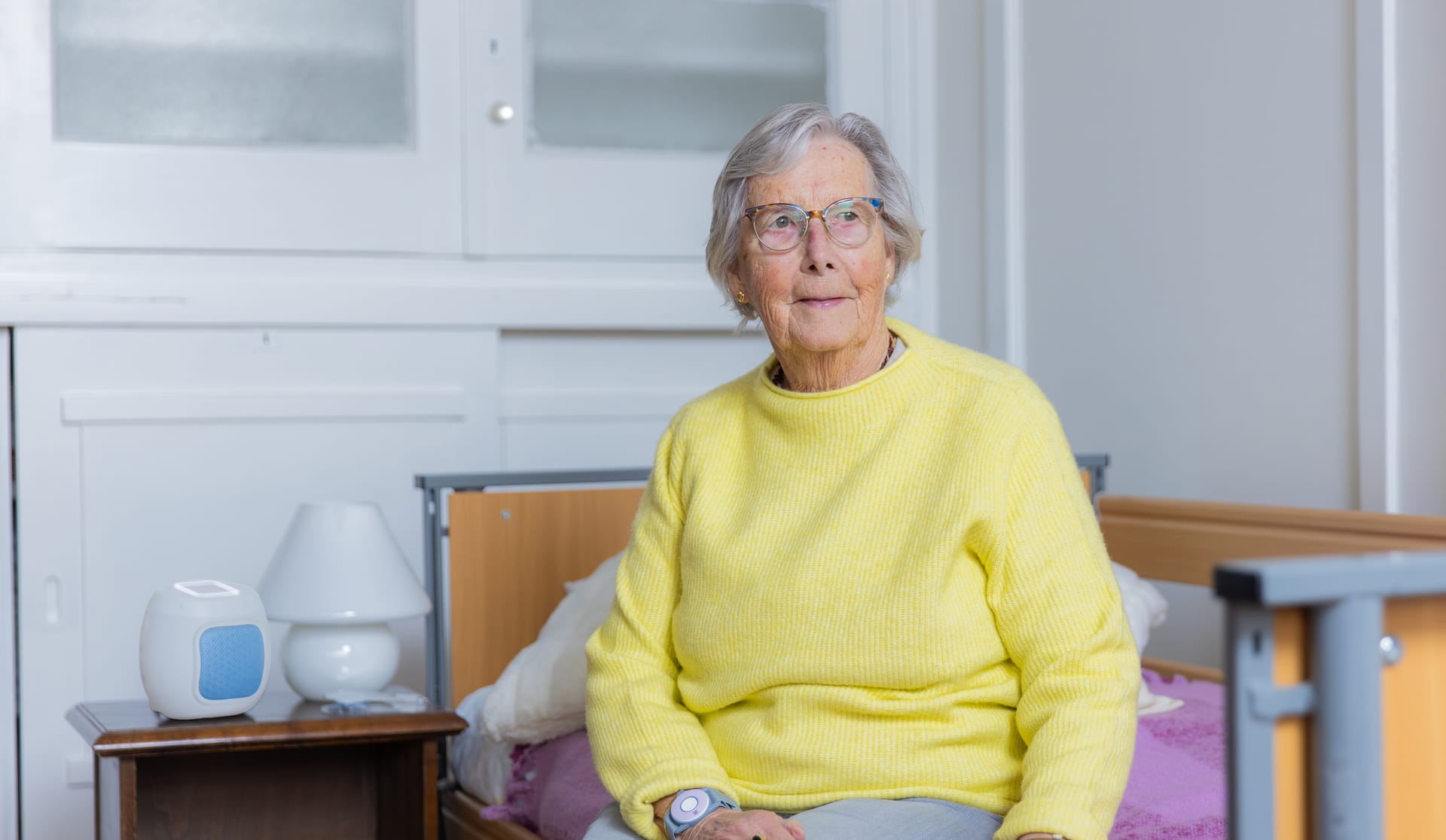 Een bewoner zit op bed met de Momo sensor op het nachtkastje